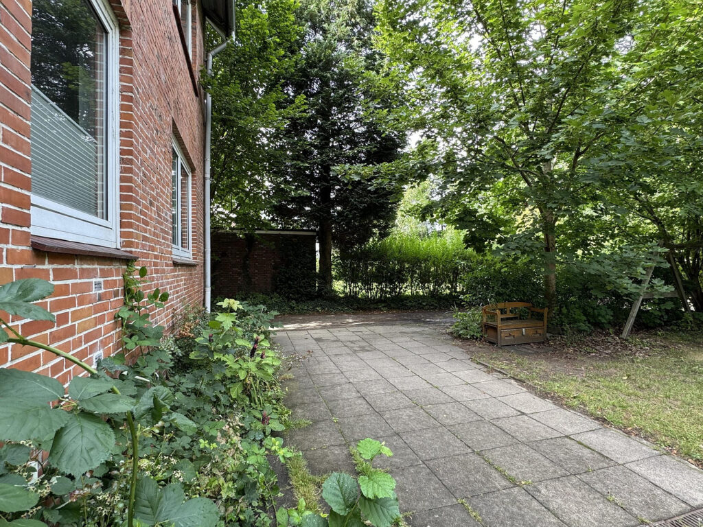 Ruhiger Außenbereich mit Sitzbank und altem Baumbestand