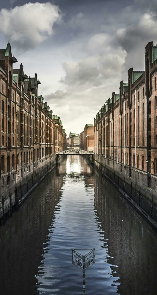 pexels-photo-221529-221529 Scenic view of Hamburg's Speicherstadt with brick warehouses and a reflective canal.